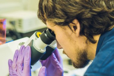 Bilim adamı işe biyolojik örnekler soruşturma için bir laboratuvar confocal tarama mikroskop üzerinde.