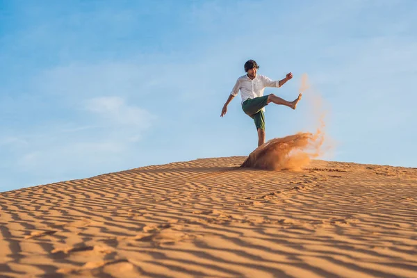 A man is kicking sand in a red desert — Stock Photo, Image