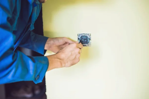 Ein junger Elektriker installiert einen elektrischen Schalter in einem neuen hou — Stockfoto
