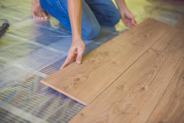 Людина встановлює нові дерев'яні ламіновані підлоги — стокове фото