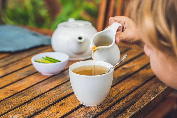 Felice bel ragazzo versa il miele nel tè — Foto Stock