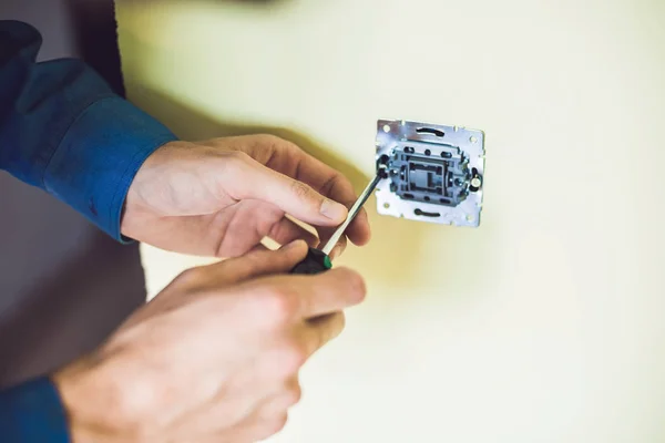 Un joven electricista instalando un interruptor eléctrico en una casa nueva —  Fotos de Stock