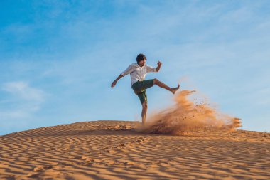 Bir adam bir kırmızı çölde kum tekme atıyor