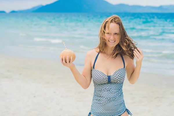 Mujer joven bebiendo leche de coco en la playa . —  Fotos de Stock