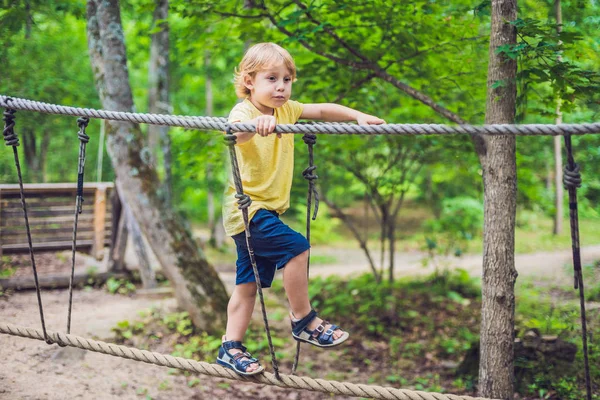 Retrato de menino bonito caminha em uma ponte de corda — Fotografia de Stock