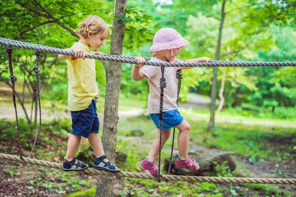 Kleine jongen en meisje lopen op een touwbrug — Stockfoto