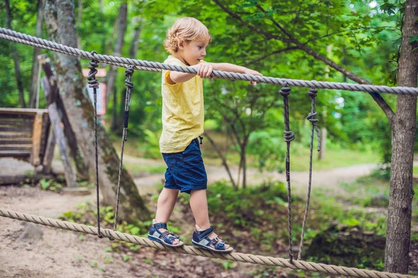 Retrato de menino bonito caminha em uma ponte de corda — Fotografia de Stock