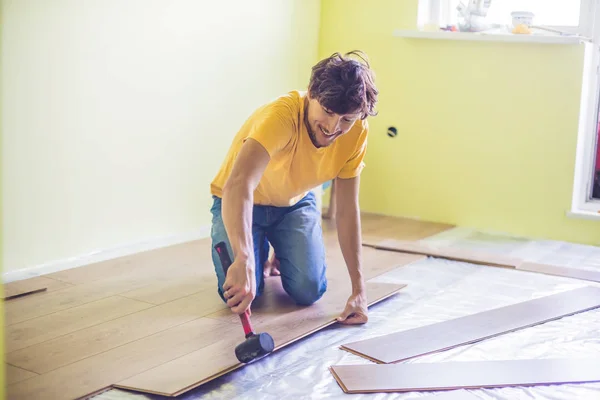 Uomo l'installazione di nuovi pavimenti in laminato di legno — Foto Stock