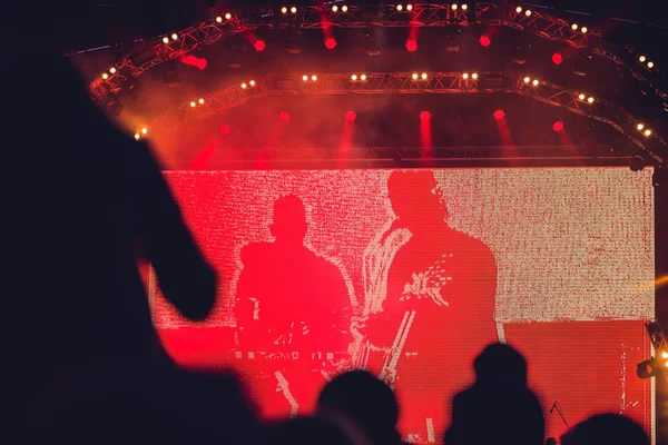 Silueta de una gran multitud en concierto contra un escenario brillantemente iluminado — Foto de Stock
