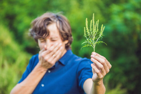 Young man sneezes because of an allergy