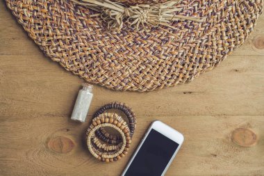 Yaz tatili, tatil, gevşeme kavramı. Hasır şapka, cep telefonu, akıllı telefon yukarıdan, üstten görünüm, ahşap arka plan üzerinde düz lay. Serbest metin kopya alanı ile renkli arka plan. Yaz vibes kavramı.