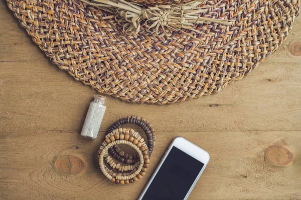 Yaz tatili, tatil, gevşeme kavramı. Hasır şapka, cep telefonu, akıllı telefon yukarıdan, üstten görünüm, ahşap arka plan üzerinde düz lay. Serbest metin kopya alanı ile renkli arka plan. Yaz vibes kavramı.