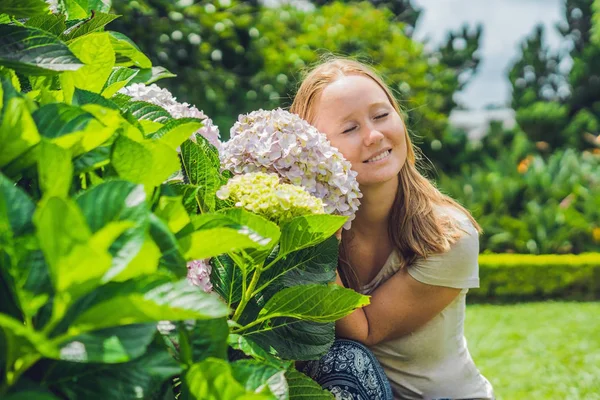 Arka planda hafif pembe ortanca çiçek bahçede çiçek açan genç kadın