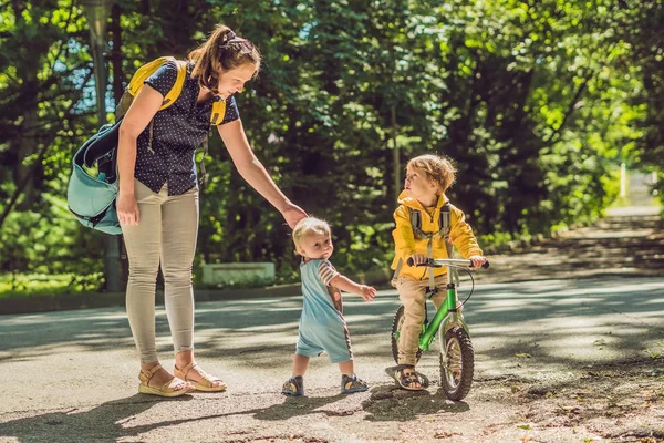 黄色のスウェットと秋の公園で母親に二人の幸せな兄弟 — ストック写真