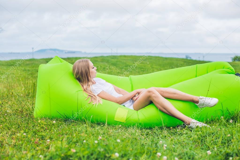 Young woman resting on an air sofa in the park.. lamzac