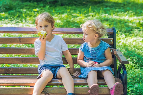 幼児の男の子と女の子の海沿いのベンチに座ってリンゴを食べると — ストック写真