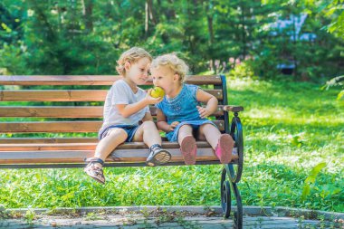 Yeni yürümeye başlayan çocuklar çocuk ve deniz kenarında bir bankta oturan kız ve bir elma yemek