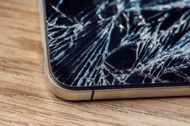 Yünlü bir masada kırık camlı akıllı telefon ekranı.