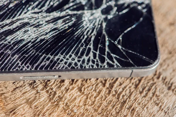 Smartphone display with broken glass on a wodden table