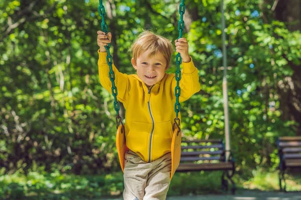 Sarı bir kazak bir çocukta salıncakta bir sahada sonbaharda oturur