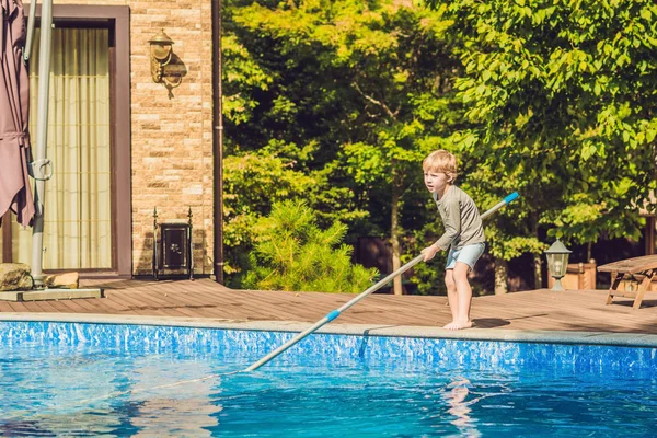 Το αγόρι Toddler καθαρίζει την πισίνα και βγάζει την μπάλα έξω από την πισίνα. Πισίνα καθαρότερη αντίληψη — Φωτογραφία Αρχείου