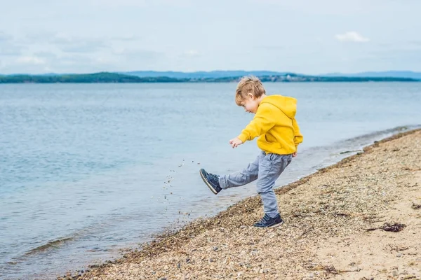 Jovem rapaz atirando pedras na água do mar — Fotografia de Stock