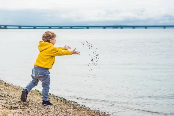 Мальчик бросает камни в морскую воду — стоковое фото