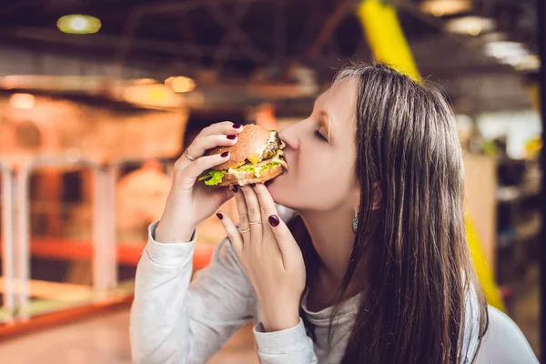 Young woman eating hamburger woman eating junk food, fatty food hamburger.