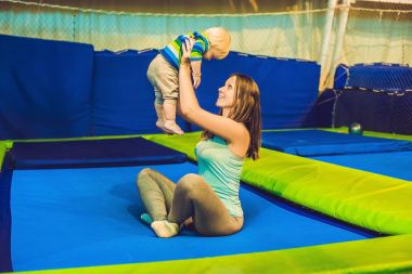 Anne ve oğlu fitness Park'ta bir trambolin üzerinde atlama ve kapalı exersice yapıyor.