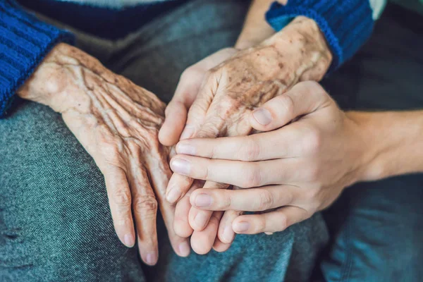 Handen van de oude vrouw en jonge man — Stockfoto
