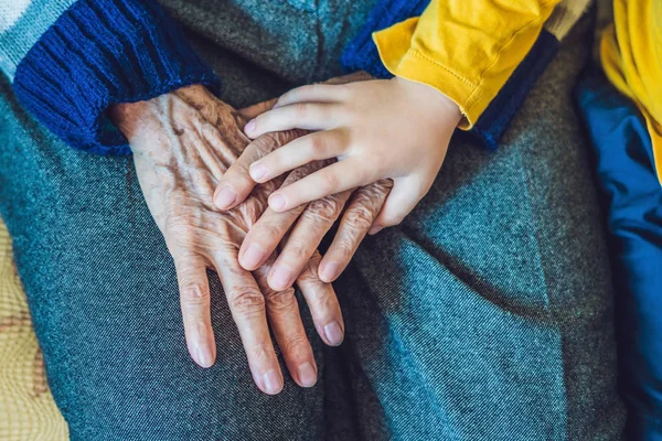 Le mani di un anziano e le mani di un bambino, la continuità delle generazioni, la cura degli anziani — Foto Stock