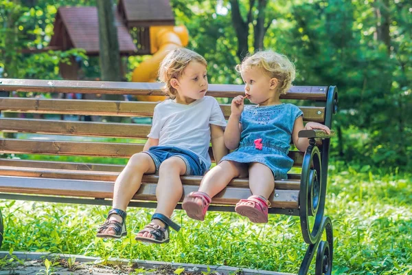 幼児の男の子と女の子の海沿いのベンチに座って パン棒を食べる — ストック写真