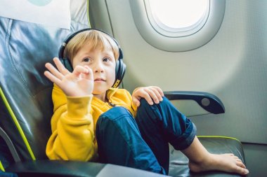 Çocuk izliyor ve uçak gemide uçuş eğlence dinlerken kulaklık ile.