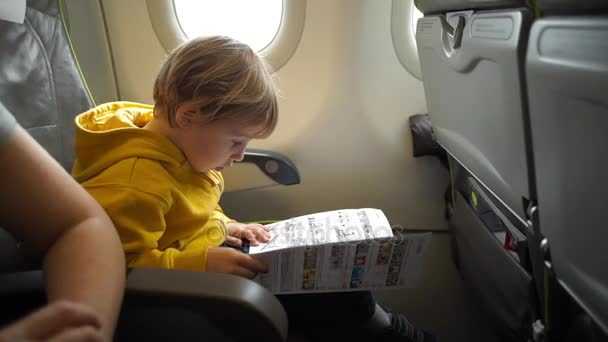 Мальчик с наушниками, смотрящий и слушающий в летных развлечениях на борту самолета — стоковое видео