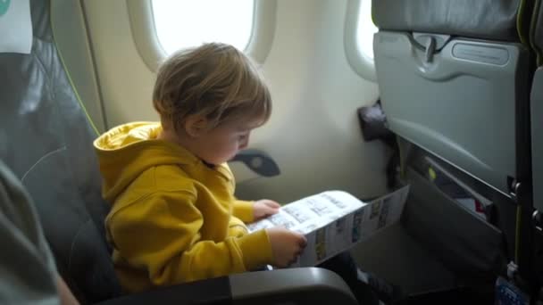 Niño con auriculares viendo y escuchando en vuelo entretenimiento a bordo del avión — Vídeos de Stock