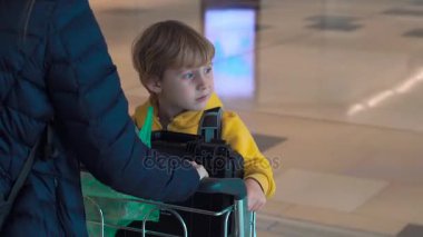 Steadycam atış oğluyla bir arabası üzerinde duran bir havaalanında yürüyen genç bir kadın 
