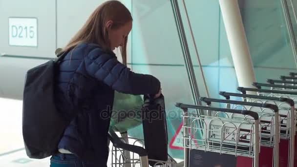 Slowmotion 拍摄的一个年轻女子在机场采取手推车 — 图库视频影像