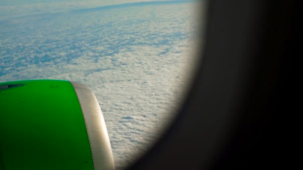 Reveal shot of a a green airplane flying over clouds view from a window on an engine — Stock Video