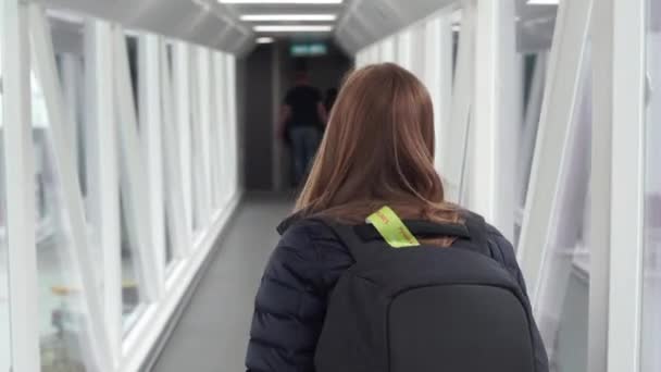 Schwebestativ-Aufnahme einer Frau, die auf einem Fußweg zwischen dem Flughafen und dem Flugzeug geht — Stockvideo