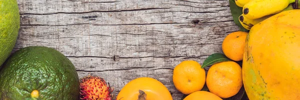 Banner, lange formaat kleurrijke vruchten op de witte houten tafel, bananen, carambola's, mango, papaya, Mandarijn, ramboetan, pamela, kopie ruimte — Stockfoto