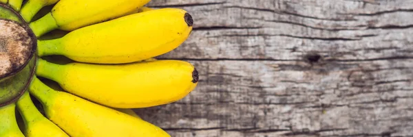 BANNER, Long Format Ramo de plátanos amarillos orgánicos maduros crudos sobre fondo de madera —  Fotos de Stock