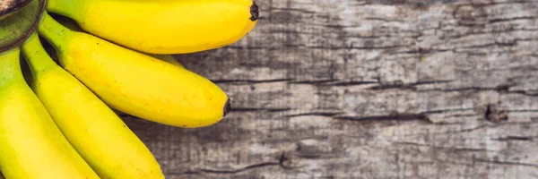 BANNER, Long Format Ramo de plátanos amarillos orgánicos maduros crudos sobre fondo de madera —  Fotos de Stock