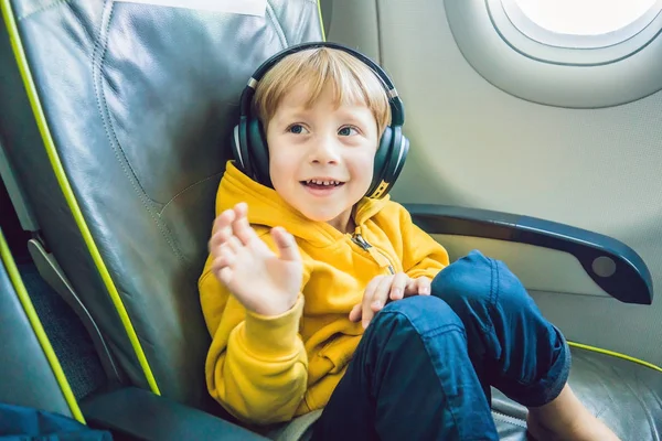 Мальчик с наушниками, смотрящий и слушающий в летных развлечениях на борту самолета — стоковое фото