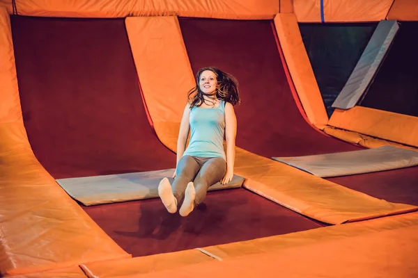 Joven deportista saltando en un trampolín en el parque de fitness y haciendo exersice en interiores —  Fotos de Stock