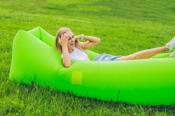 Mujer joven descansando en un sofá de aire en el parque. — Foto de Stock