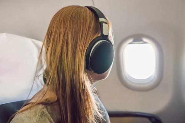Utasszállító repülőgép fejhallgató használata. Nő a repülőgép kabin zenehallgatás fejhallgató. — Stock Fotó