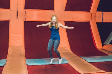 Fitness Park'ta bir trambolin üzerinde atlama ve exersice kapalı yapıyor genç kadın sporcu.