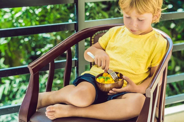 Маленький милый мальчик ест манго — стоковое фото