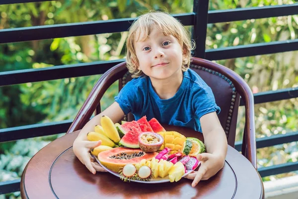 Niño comiendo diferentes frutas — Foto de Stock