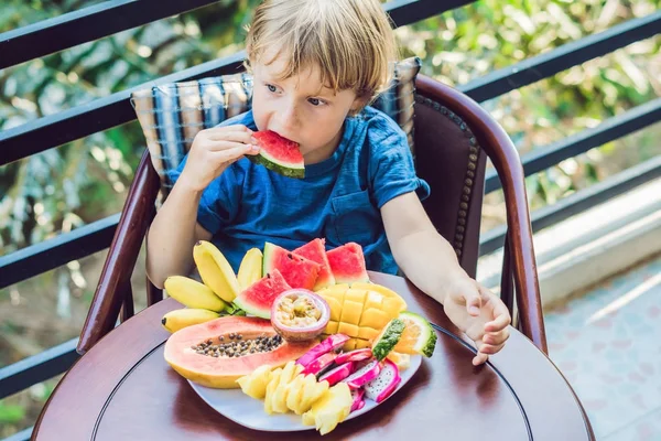 Niño comiendo diferentes frutas — Foto de Stock